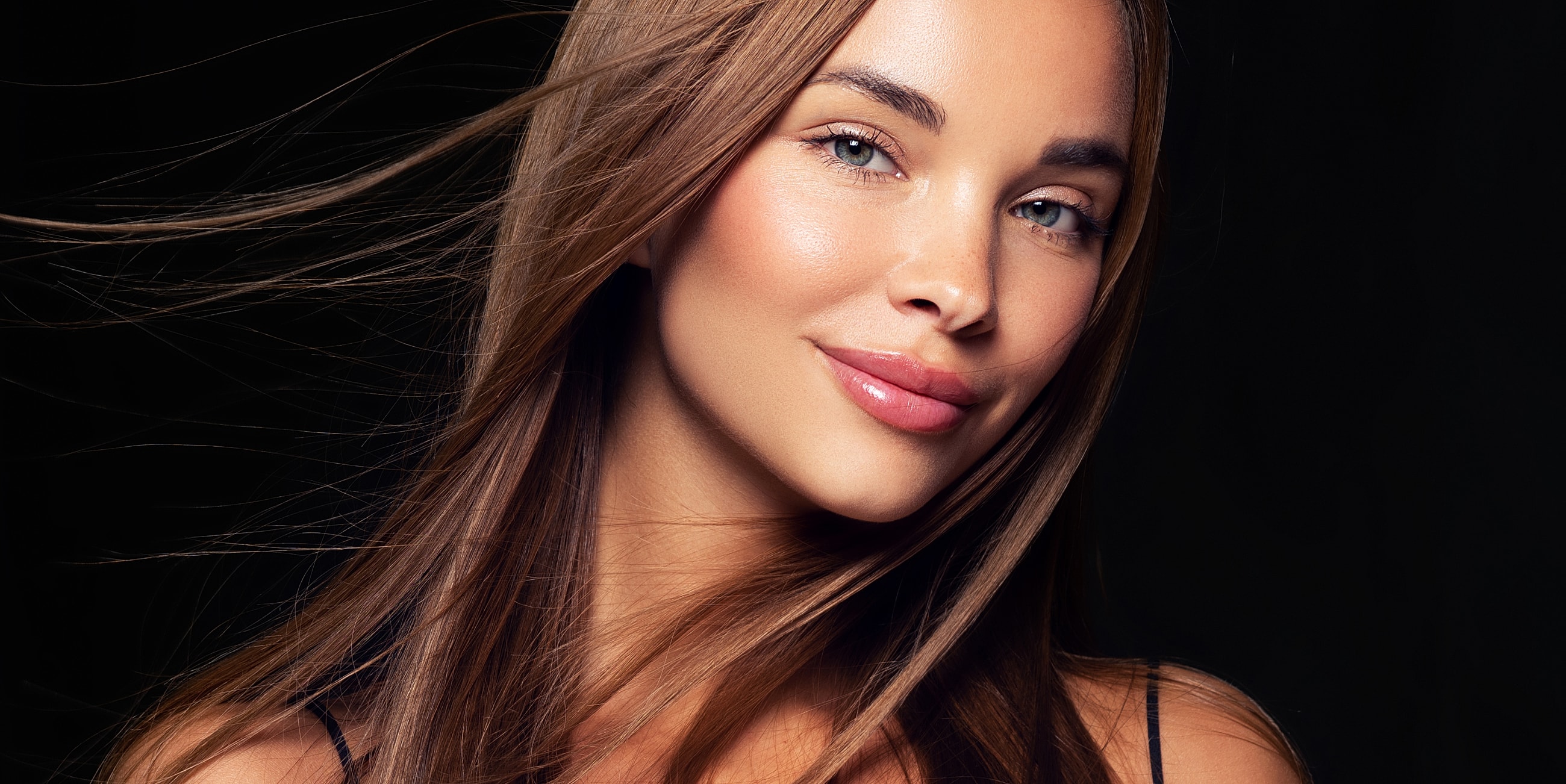 Woman with long hair against dark background.